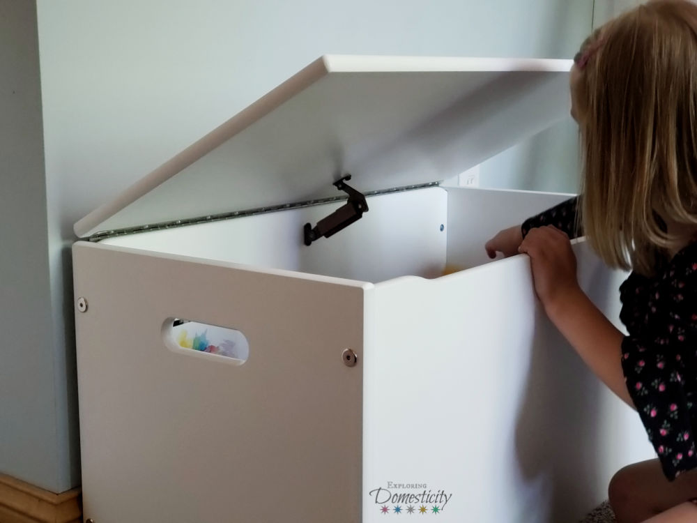 girl putting toys in toy box
