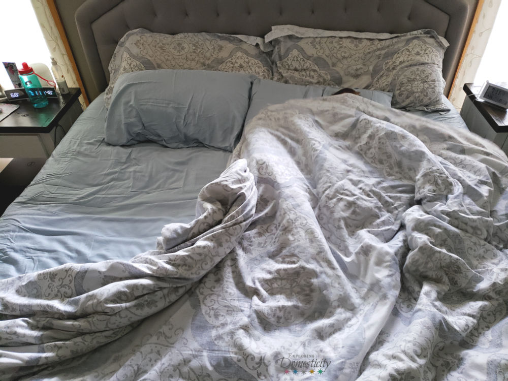 messy bed with child hiding under the covers