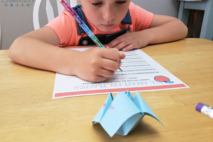 Kindergartner filling out her Teacher Appreciation Questionnaire with a cootie catcher in front of her