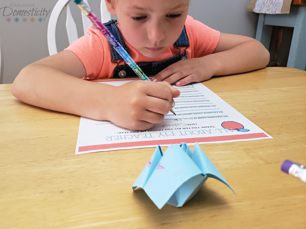 Kindergartner filling out her Teacher Appreciation Questionnaire with a cootie catcher in front of her