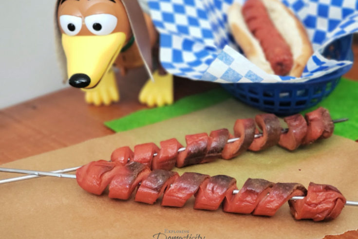 Campfire Slinky Dogs - two hot dogs cut in spirals on roasting sticks with a slinky dog toy and a spiralized hot dog in a bun in a basket