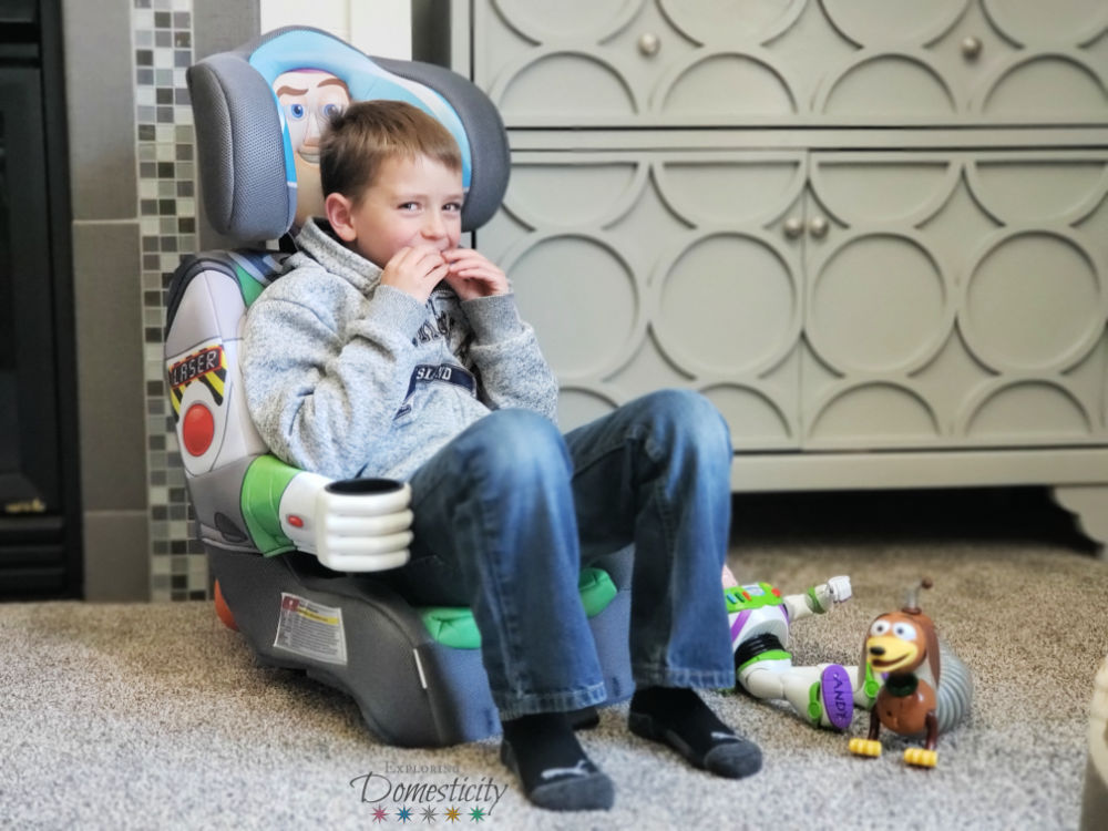 Kid eating campfire slinky dogsin a KidsEmbrace Buzz Lightyear carseat with Buzz and Slinky Dog toys 