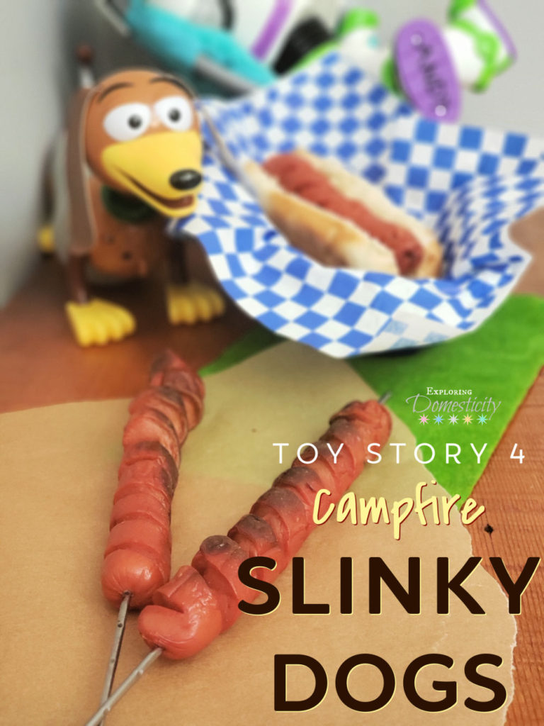 Toy Story 4 Campfire Slinky Dogs - 2 hot dogs on roasting sticks and one spiral hot dog in a bun in a basket next to Slinky Dog and Buzz Lightyear