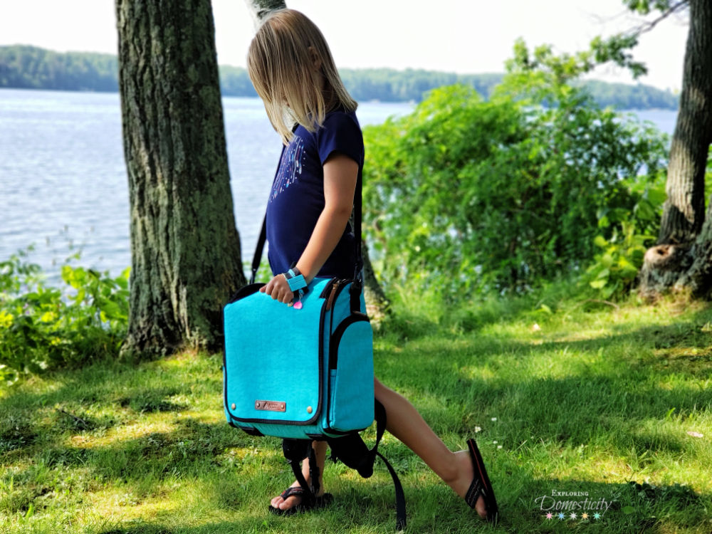 Girl at the lake walking with a MOOV Grow messenger bag