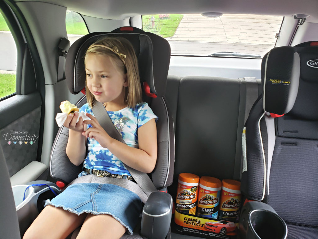 little girl in car seat eating an apple